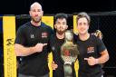 Charlie Falco with his Cage Warriors Academy straw-weight title and coaches Jack Mason and Leigh Mitchell